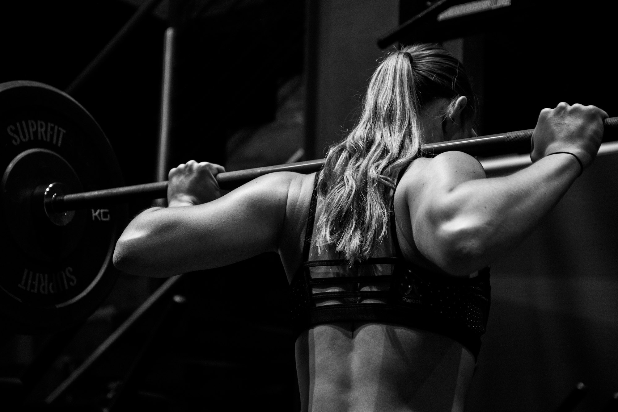 A barbell squat under the bar — strength, measured